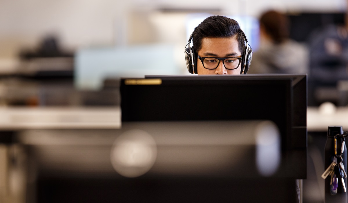 A student wearing headphones works on a computer
